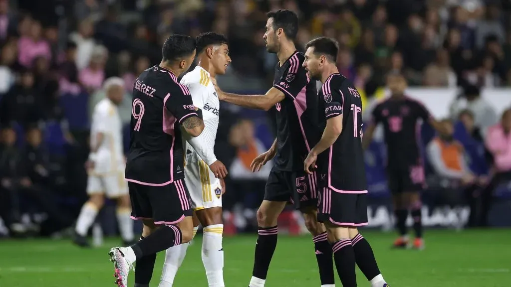 Edwin Cerrillo #20 of Los Angeles Galaxy is restrained by Luis Suárez #9 and Sergio Busquets #5 of Inter Miami as he lunges at Lionel Messi #10 of Inter Miami during the first half of a game at Dignity Health Sports Park on February 25, 2024 in Carson, California.