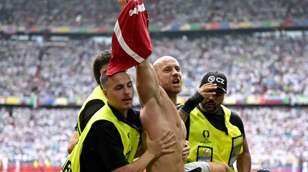 A streaker is taken away by stewards