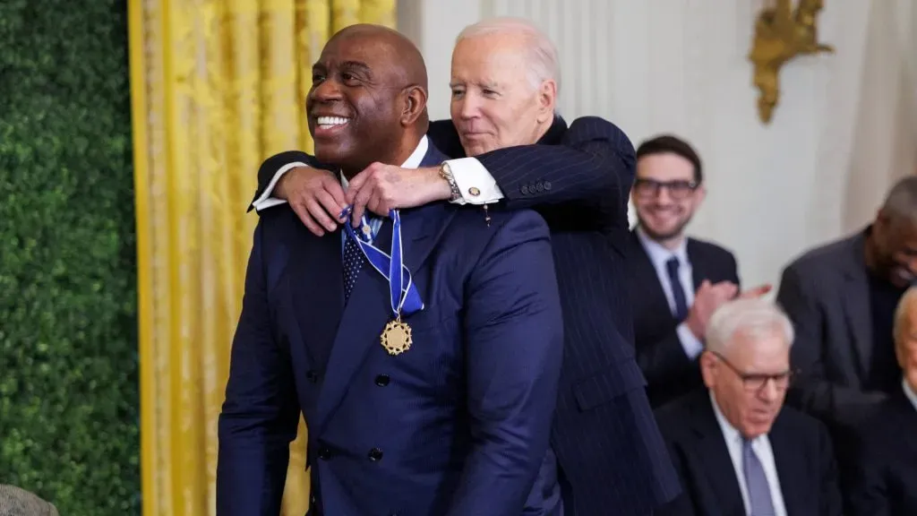 Magic Johnson crouches while being awarded the Presidential Medal of Freedom by U.S. President Joe Biden. (Tom Brenner/Getty Images)