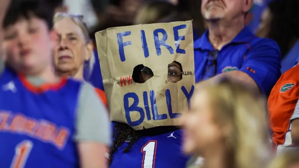 Florida Gators fan wears a brown paper bag on their head that says “Fire Billy”