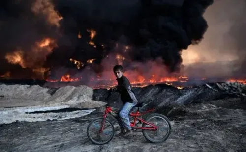 Un niño pasea por su bicicleta en medio de un campo de batalla (Getty Images)