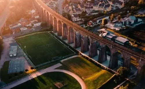 Apretada entre un puente ferroviario y una autopista brilla este césped (Fuente: Unsplash)