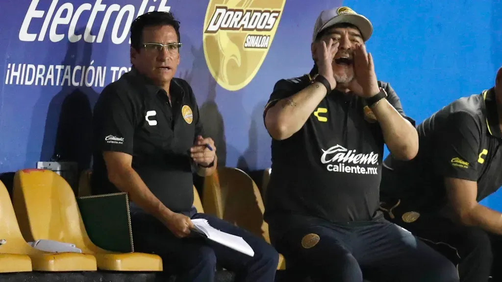García, sentado a la par de Diego Maradona, en un partido de Dorados. (Foto: AFP)