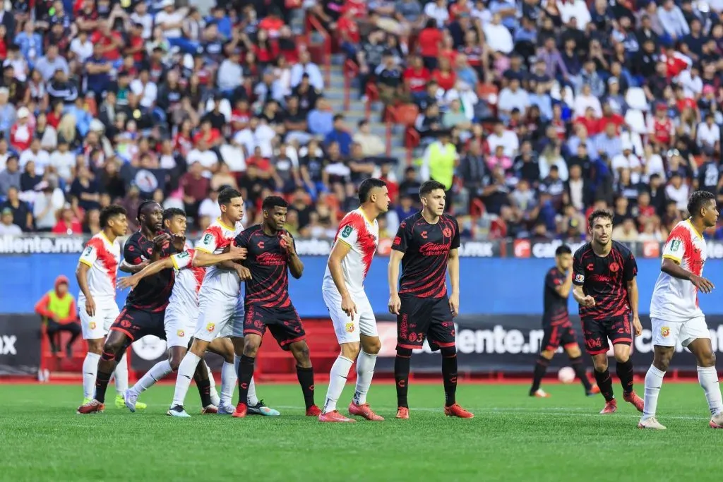 Juan Luis Pérez, el penúltimo de Herediano, marca por la espalda a uno de los jugadores de los Xolos. (Foto: Herediano)