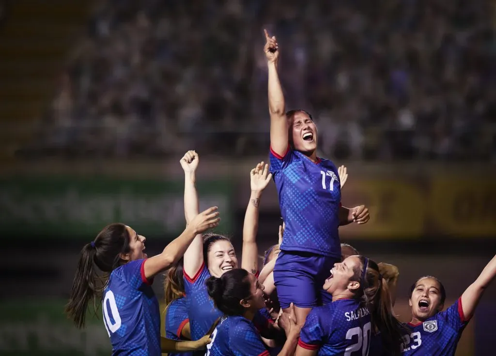 Elated team of athletic women footballers cheeringly lift up their teammate and celebrate after an important win
