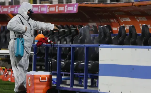 Un trabajador sanitiza el banco de suplentes. Foto: Getty