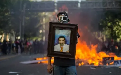 Un manifestante posa con un cuadro de Felipe Camiroaga, comunicador fallecido en 2011 en un accidente aéreo cuando se dirigía a Juan Fernández con su equipo de TVN. Desde que encaró en vivo al entonces ministro del Interior, Rodrigo Hinzpeter, por la termoeléctrica Barrancones en Punta de Choros fue muy bien visto desde el lado de las luchas sociales. También apoyó la llamada “revolución pingüina”.