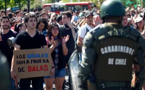 Un manifestante le exhibe este cartel a un efectivo de Carabineros. Esto dados los fallecidos por acción de agentes de Estado en casos en que el Instituto Nacional de Derechos Humanos y inició acciones legales.