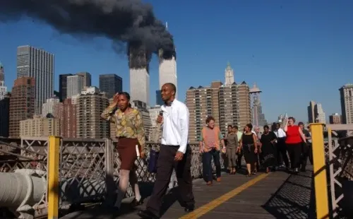 Personas caminan sobre el puente de Brooklyn mientras el World Trade Center arde | Foto: Getty Images