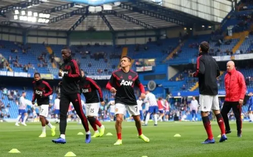 Alexis Sánchez calienta y a su lado, camina Eric Bailly. (Agencia Uno).