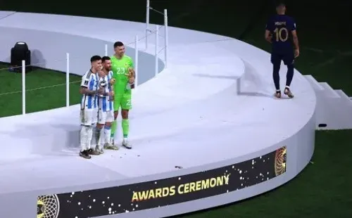 Kylian Mbappé baja del podio, mientras Lionel Messi, Enzo Fernández y Emiliano Martínez se quedan en él. (Getty Images 2022).