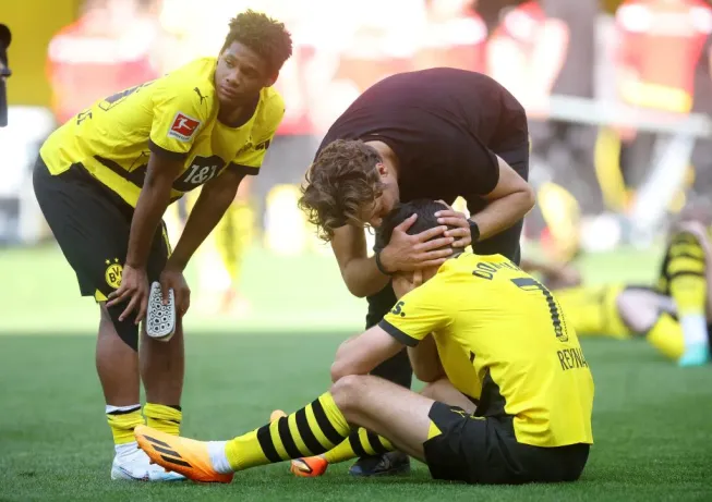Julien Duranville mira como sin entender mientras el DT del Borussia Dortmund, Edin Terzic, intenta consolar al estadounidense Giovanni Reyna. (Alex Grimm/Getty Images)