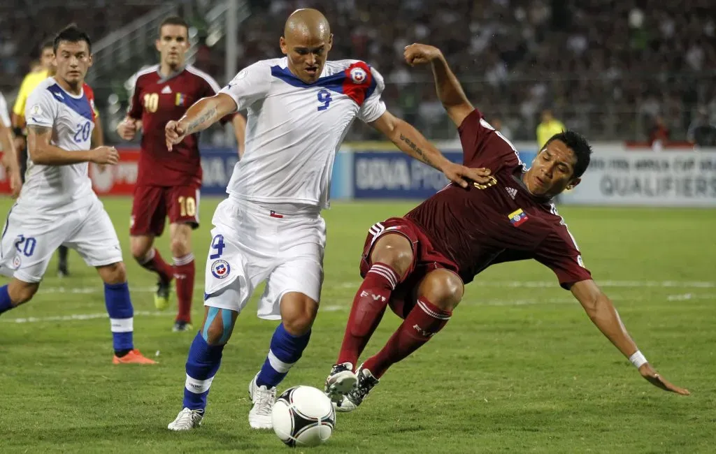 Grenddy Perozo trata de bloquear a Humberto Suazo en un duelo que Chile le ganó a Venezuela por 2-0 en las Eliminatorias rumbo a Brasil 2014. (Andrés Piña/Photosport).