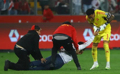 Pedro Gallese forcejea para quedarse con el teléfono móvil del hincha invasor de Perú que buscaba una foto con Messi. (Leonardo Fernandez/Getty Images).
