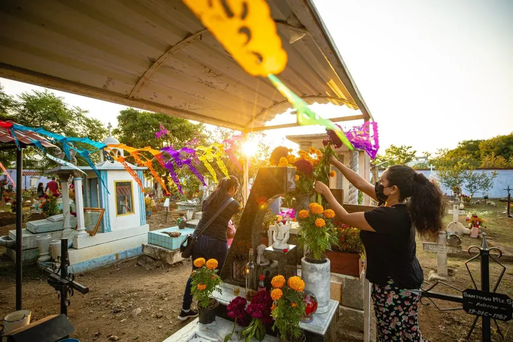 Mujer mexicana adornando tumba en el Día de Muertos