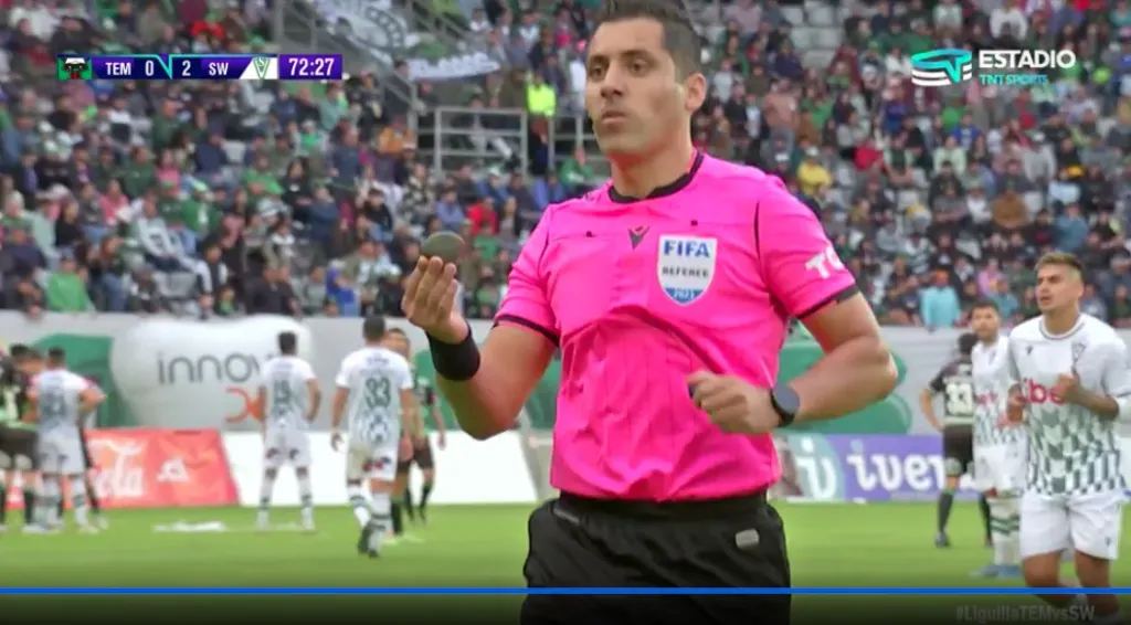 El árbitro muestra la piedra caída en la cancha del Germán Becker.