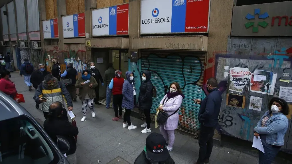 Personas hacen fila afuera de una sucursal de la Caja de Compensación Los Héroes