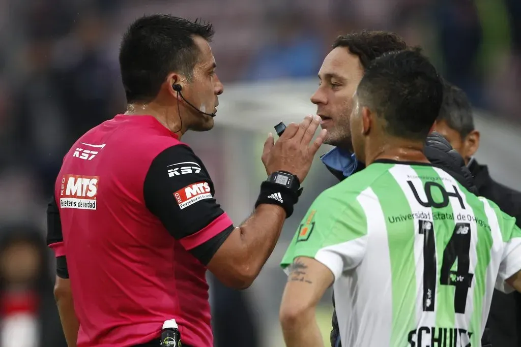 Milito le reclama a Julio Bascuñán en un partido entre Universidad de Chile y O’Higgins.  (Marcelo Hernández/Photosport).