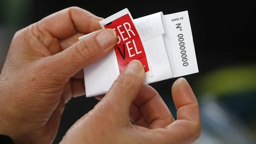 Persona pega sello del Servel en su voto