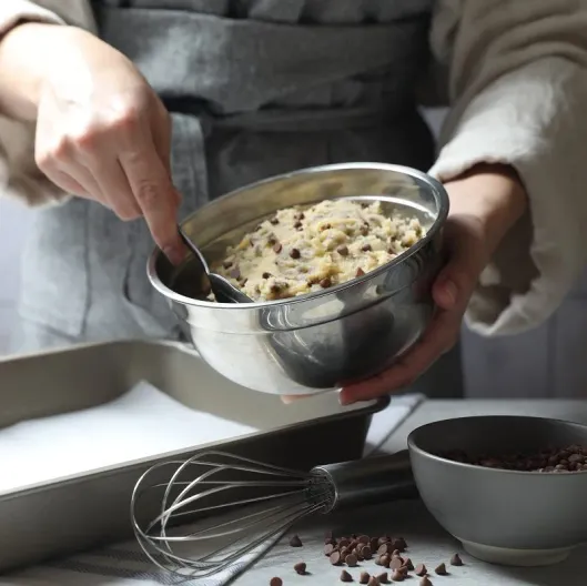 Una persona integra con una cuchara la mezcla para las galletas con chips de chocolate