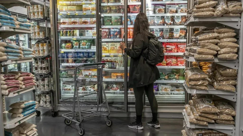 Una mujer mira productos en el pasillo de congelados de un supermercado.