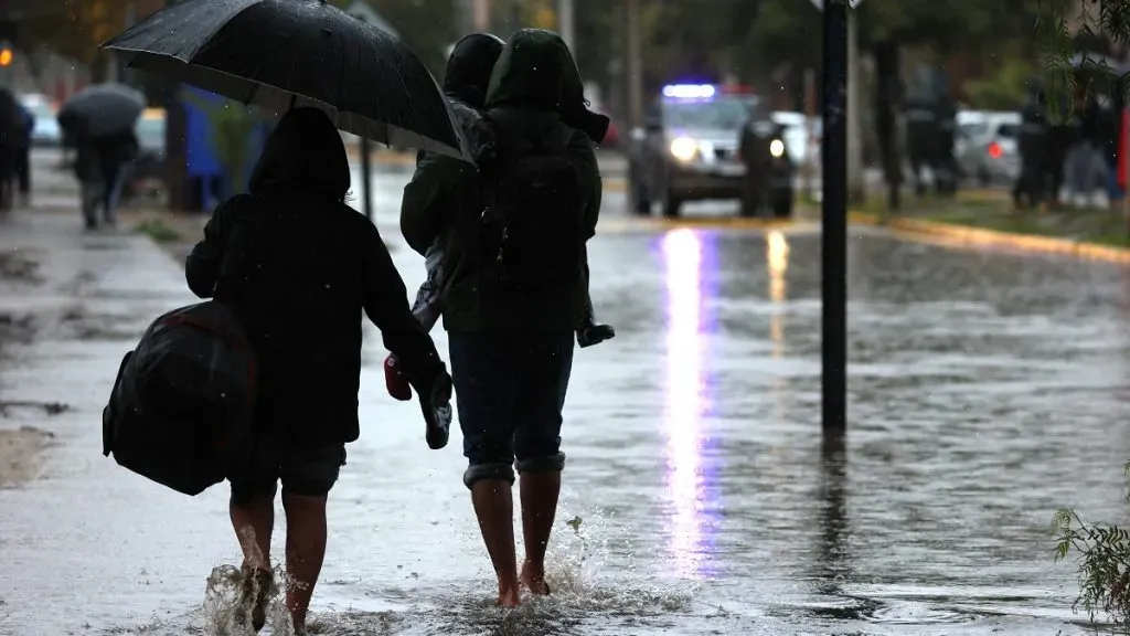 Personas caminan por una calle inundada por las lluvias en Quilicura.