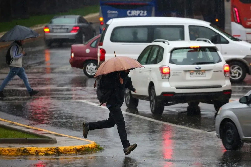 Una persona camina por la calle bajo la lluvia, cubierto con un paraguas.