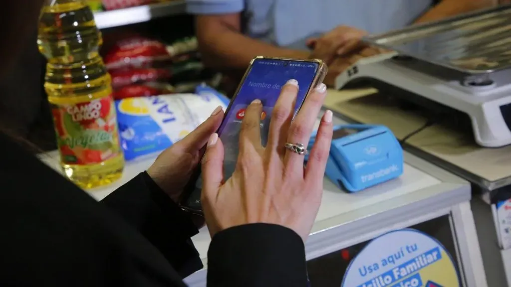 Una mujer paga una compra en un almacén con el Bolsillo Familiar Electrónico usando su teléfono.