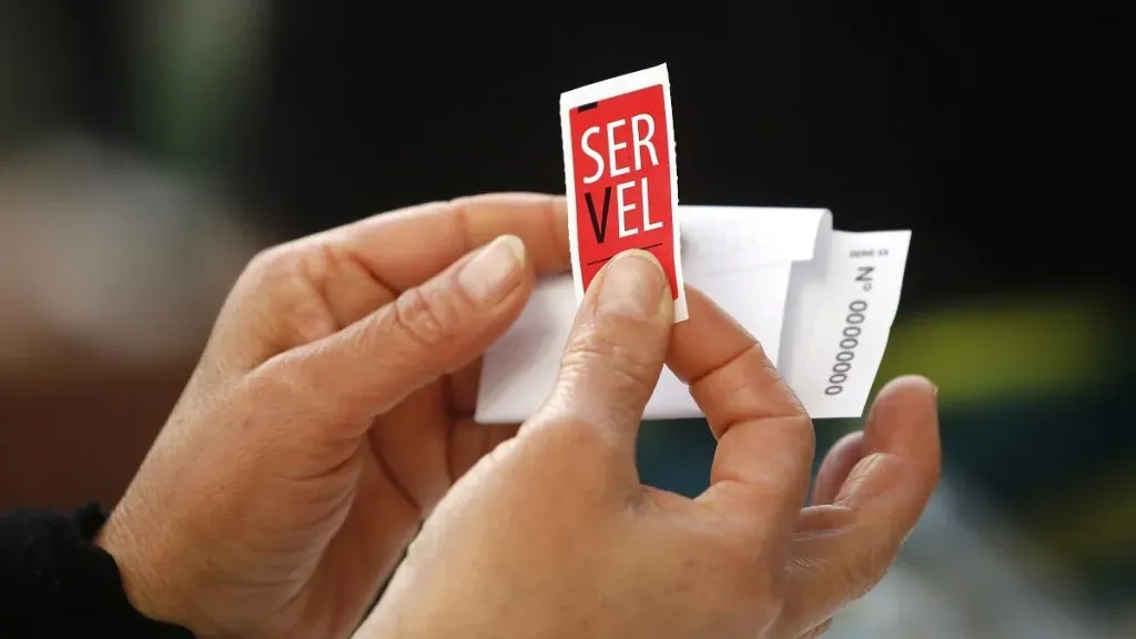 Una persona pega la estampilla del Servel en su voto antes de ingresarlo a la urna.
