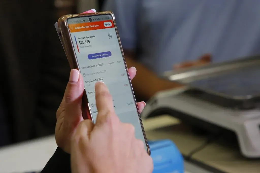 Primer plano a una mano apuntado a la app de Banco Estado en un teléfono, tras realizar una compra con Bolsillo Familiar Electrónico.