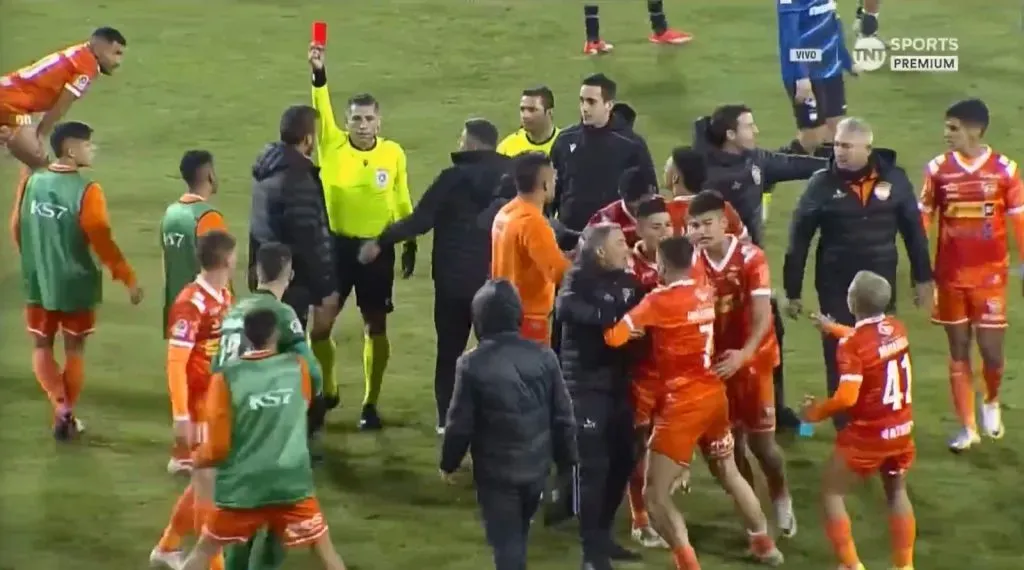 Insaurralde (7) intenta ir sobre el árbitro. Bastián Tapia y Donadell quieren controlarlo. (Captura TNT Sports).