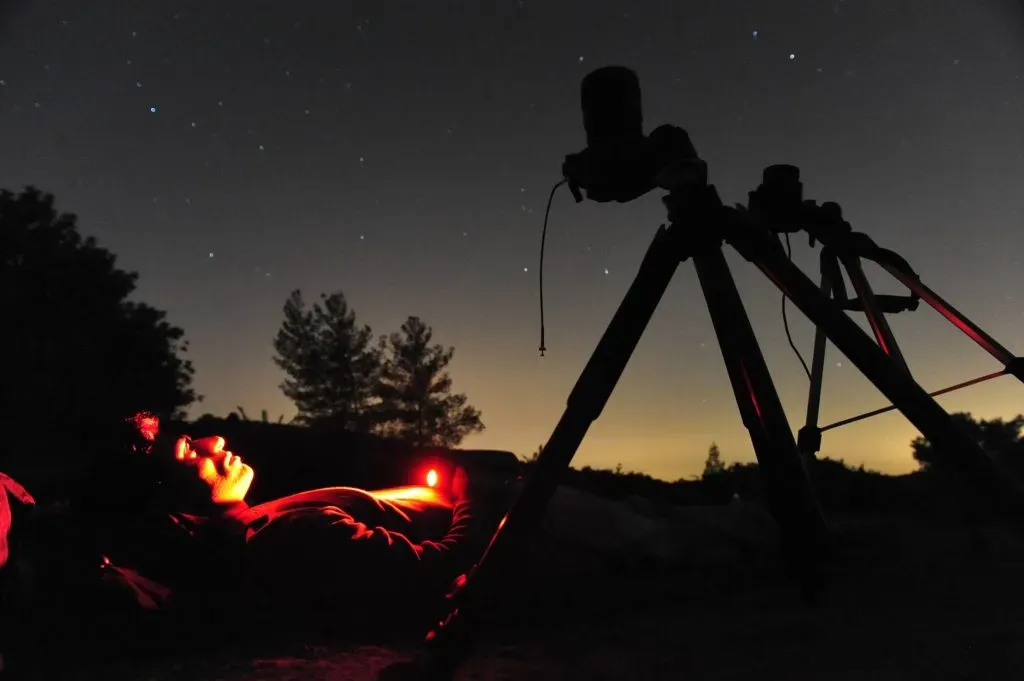 Hombre contemplando el cielo nocturno y fotografiando las estrellas