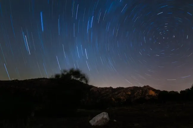 Vista de las estrellas de la Vía Láctea con la cima de una montaña en primer plano