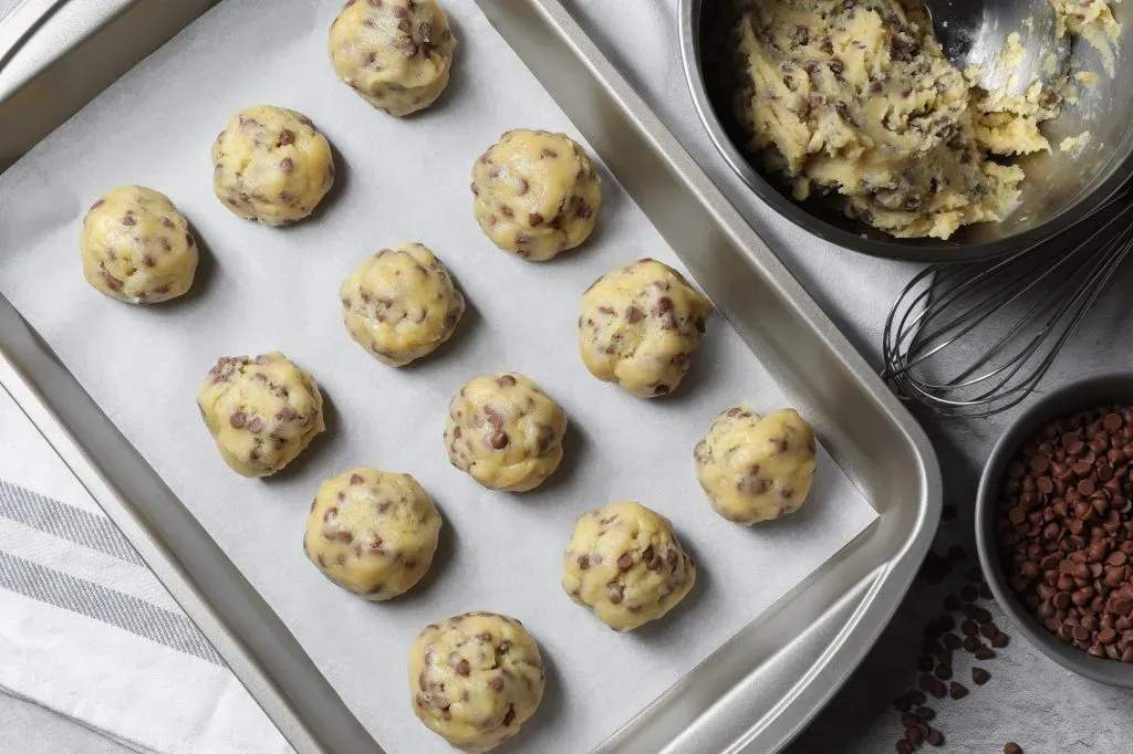 Bolas de masa de galletas con chips de chocolate en una bandeja.