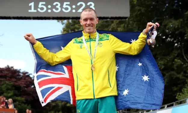 El medallista de oro, Rohan Dennis, celebra con su bandera durante la ceremonia de entrega de medallas de la contrarreloj individual masculina en la séptima jornada de Birmingham 2022 | Getty Images