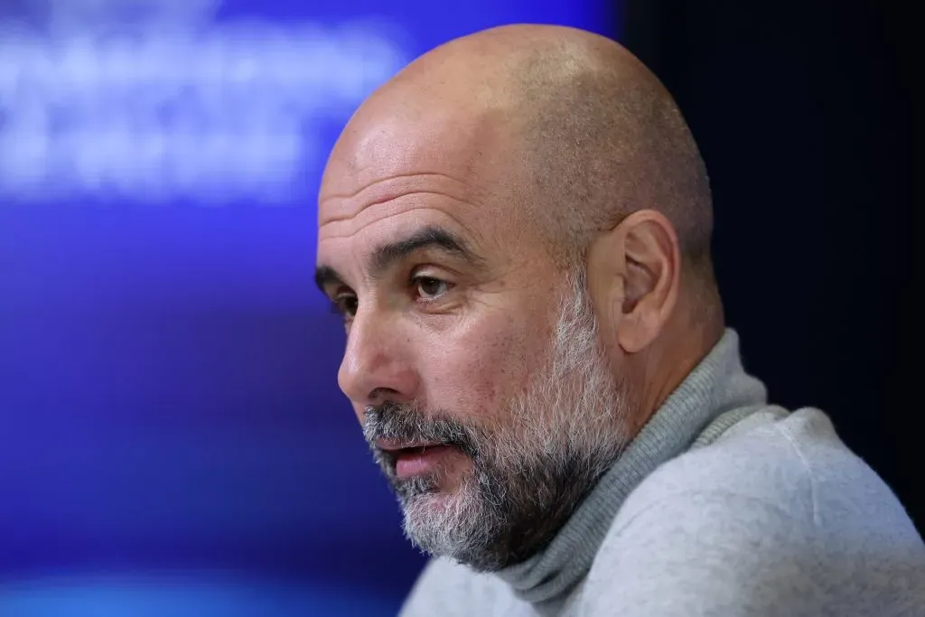 Guardiola sentado em entrevista coletiva