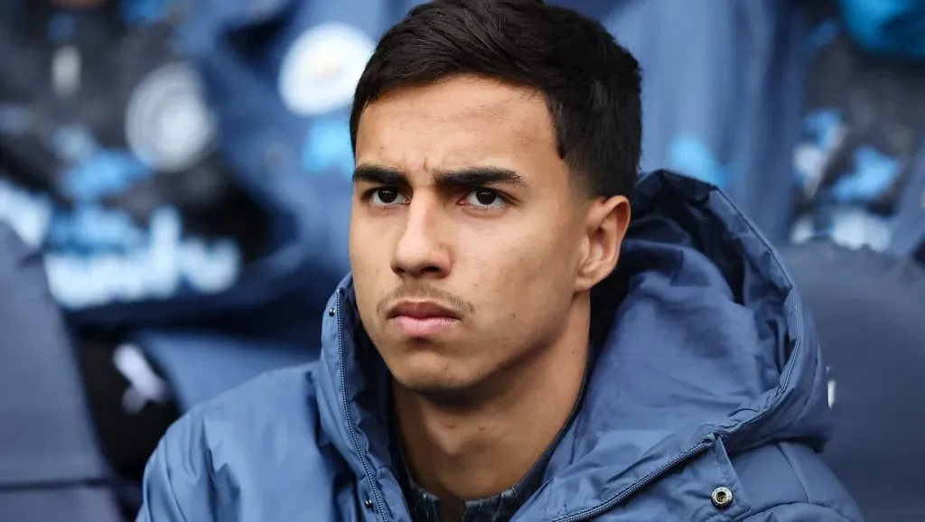 Zagueiro Vitor Reis, no banco de reservas do Manchester City, com jaqueta azul do clube (Photo by Matt McNulty/Getty Images)