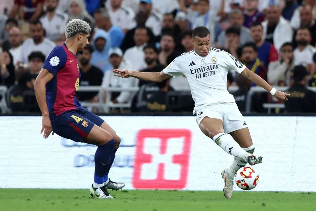 Kylian Mbappé, do Real Madrid, conduz a bola sob pressão de Ronald Araújo, do FC Barcelona, durante a final da Supercopa da Espanha entre Real Madrid e FC Barcelona, no Estádio King Abdullah Sports City, em 12 de janeiro de 2025, em Jidá, Arábia Saudita. (Foto de Yasser Bakhsh/Getty Images)