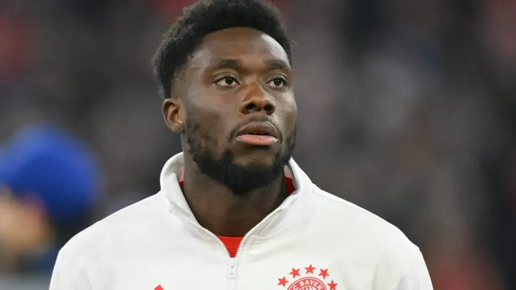 Alphonso Davies de jaqueta branca com emblema do Bayern de Munique (Photo by Sebastian Widmann/Getty Images)