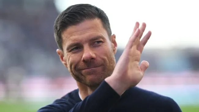 Xabi Alonso, em campo, com blusa preta e acenando com a mão, deve assumir o Real Madrid