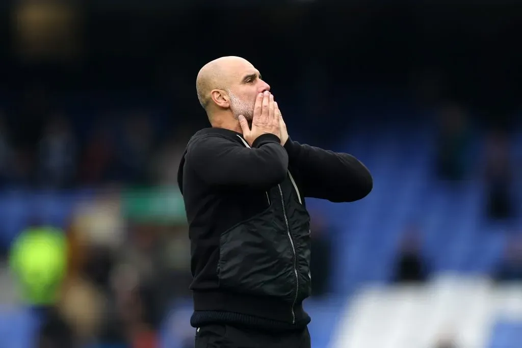 Guardiola de casaco preto e com as mãos na boca