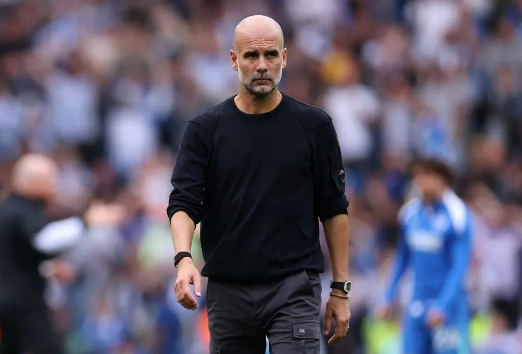 Pep Guardiola caminhando no campo de futebol