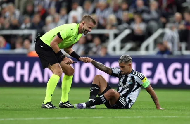 Bruno Guimarães, no chão, com a camisa listrada em Newcastle x Barcelona