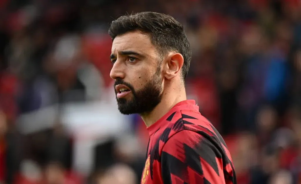 Bruno Fernandes, em campo, de camisa vermelha e preta