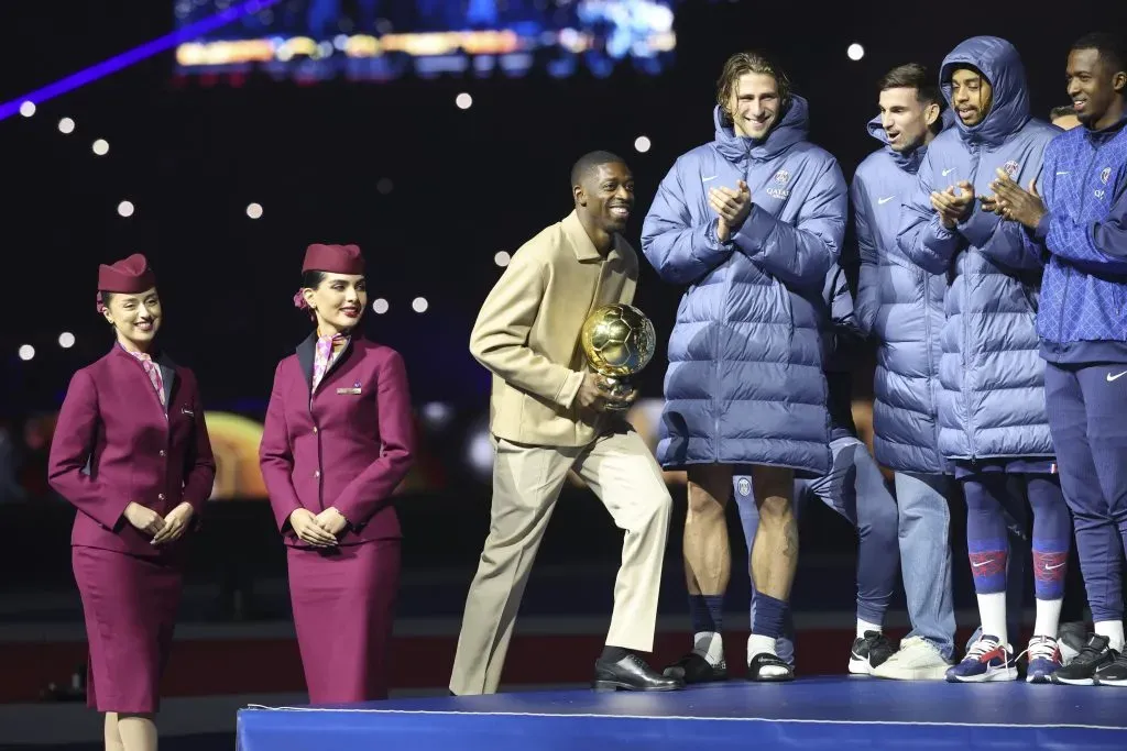 Dembélé, pelo PSG, de jaqueta bege e calça bege