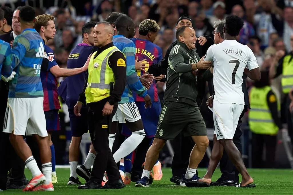 Vinicius Junior, do Real Madrid, é escoltado para fora do campo enquanto gesticula em direção a Lamine Yamal e Raphinha, do FC Barcelona, que saem do campo após a partida da LaLiga EA Sports entre Real Madrid CF e FC Barcelona no Estádio Santiago Bernabeu, em 26 de outubro de 2025, em Madri, Espanha. (Foto de Angel Martinez/Getty Images)