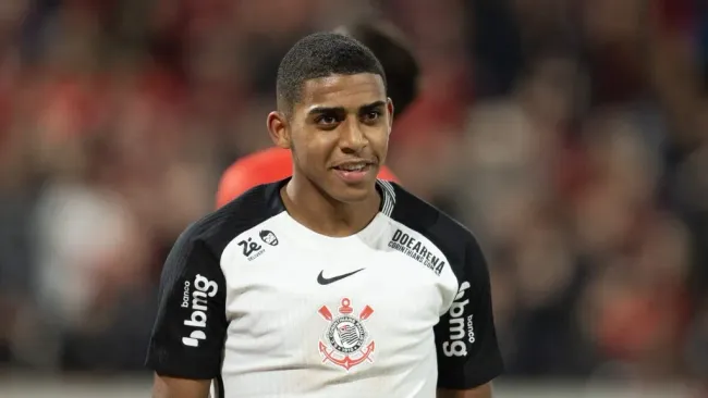 Gui Negão sorri vestindo a camisa do Corinthians que tem as cores branca com detalhes em preto nas mangas