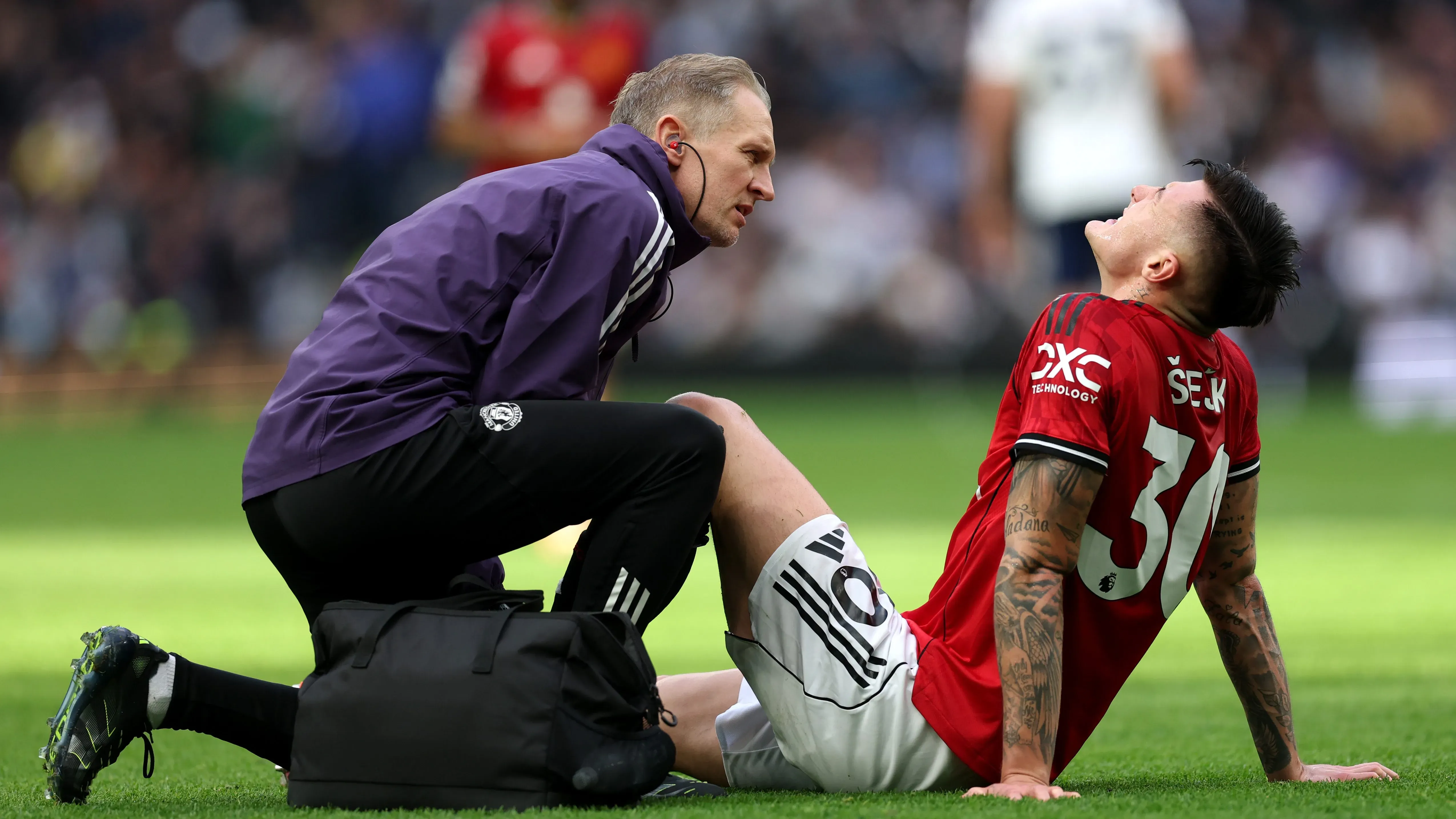 Benjamin Sesko com camisa vermelha, recebendo atendimento do médido do Manchester United. Foto: Julian Finney/Getty Images