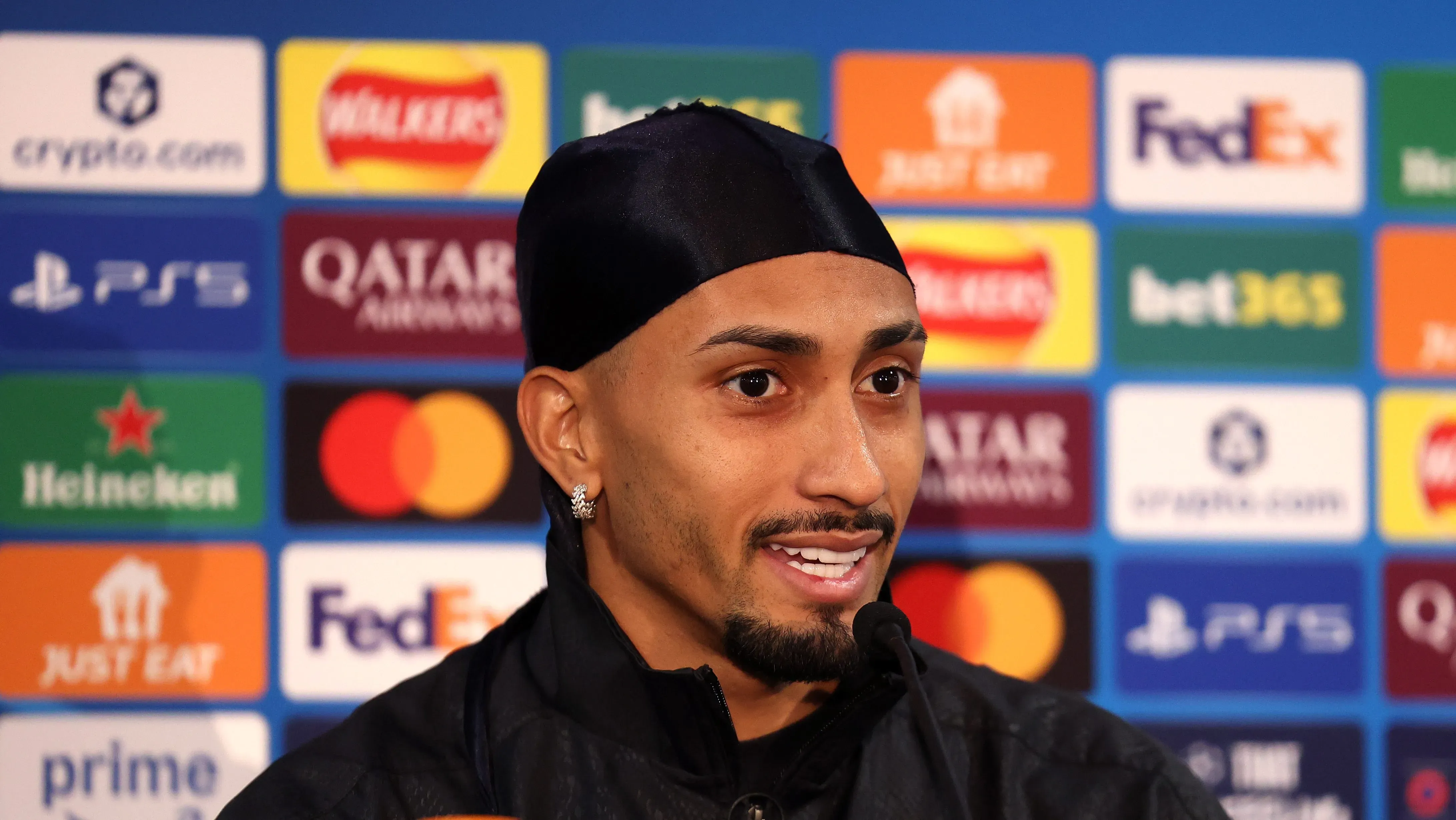 Raphinha em entrevista coletiva; jogador está usando uma espécie de bandana na cabeça