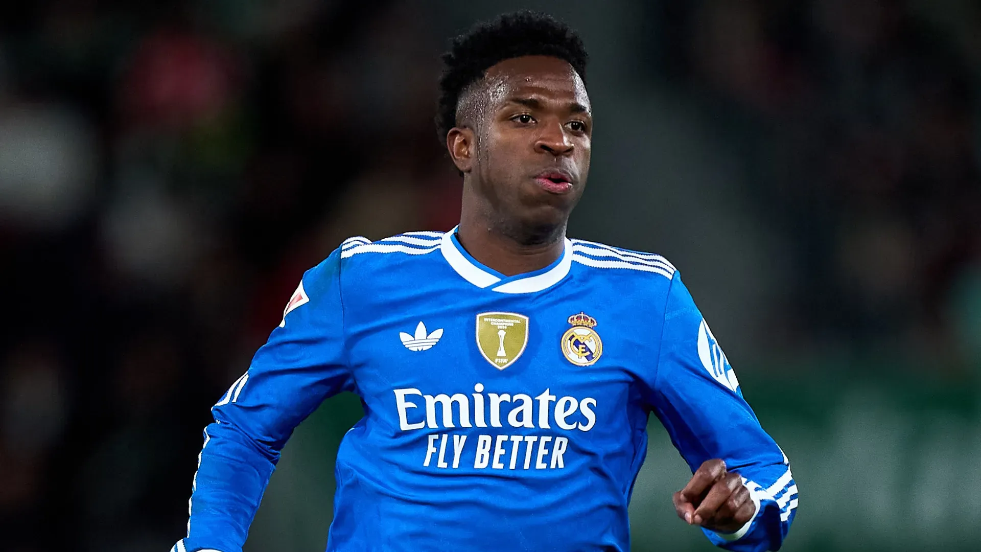 Vinicius Junior corre durante jogo com o uniforme azul do Real Madrid